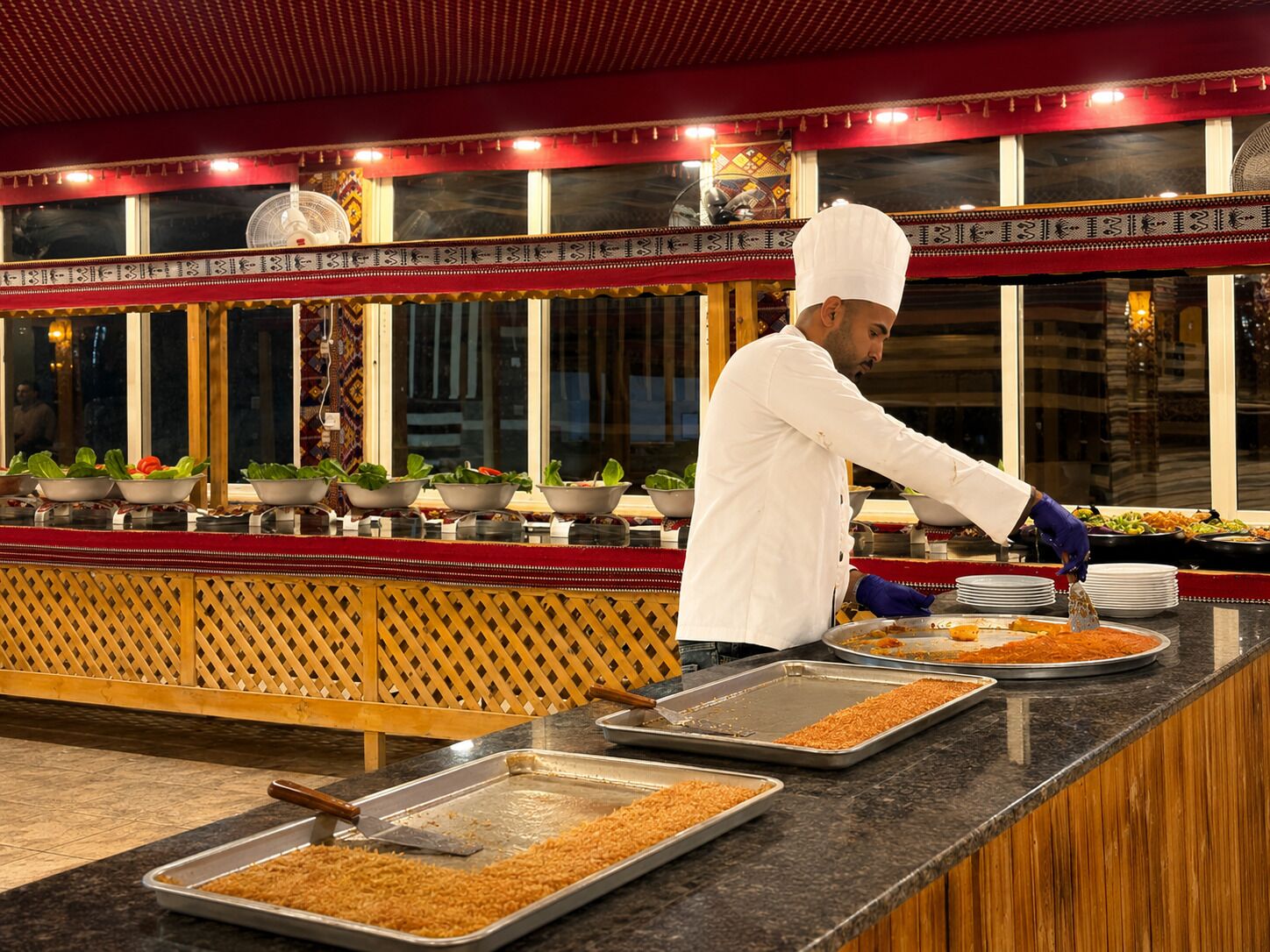 A buffet setup with various food items and a person serving.