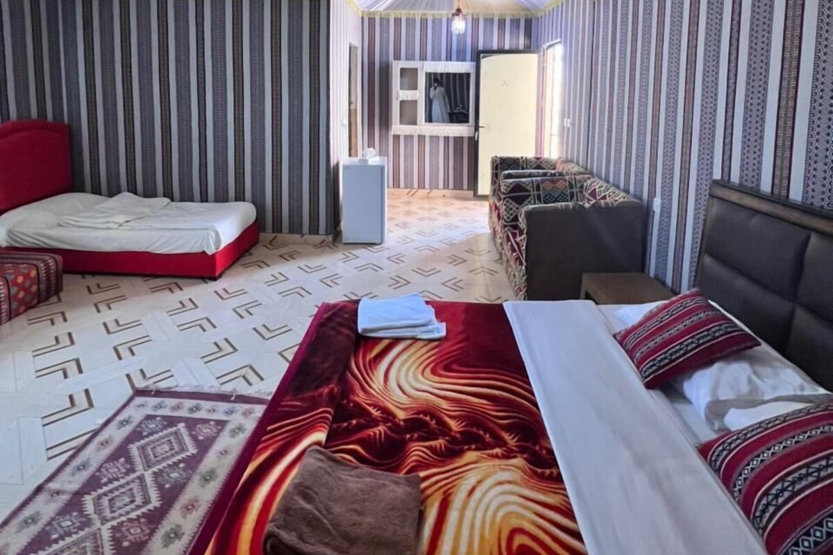 Una habitación con cama, sofá, una mesita y televisor.