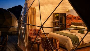A hexagonal tent with a bed, chairs, and a wardrobe.