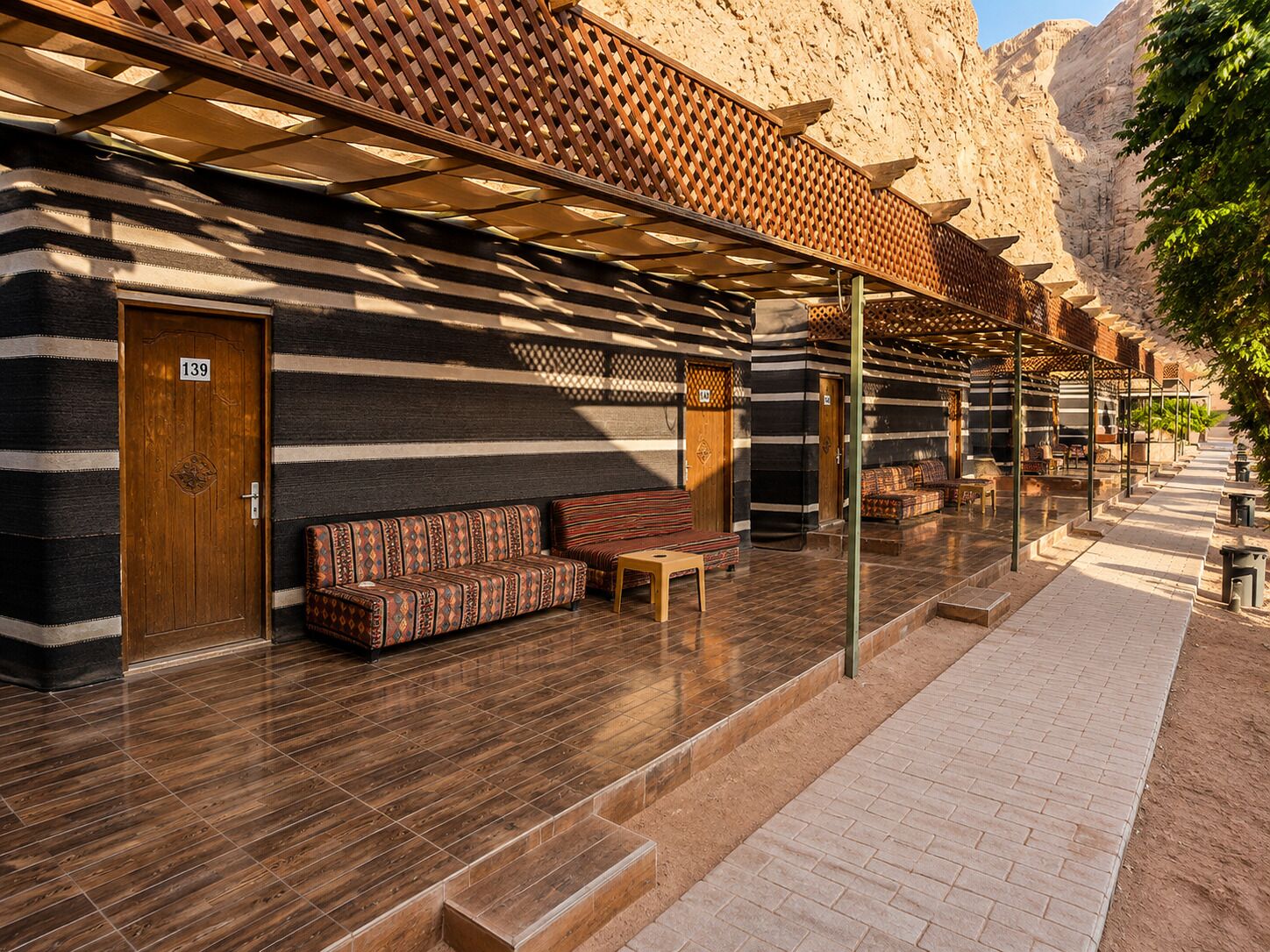 A hotel lobby with a wooden door marked '139', a patterned sofa, and a covered outdoor seating area.