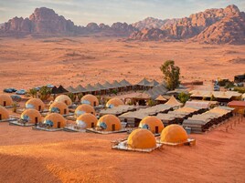 Paisaje desértico con varias tiendas de forma abovedada dispuestas en filas, rodeado de colinas rocosas.