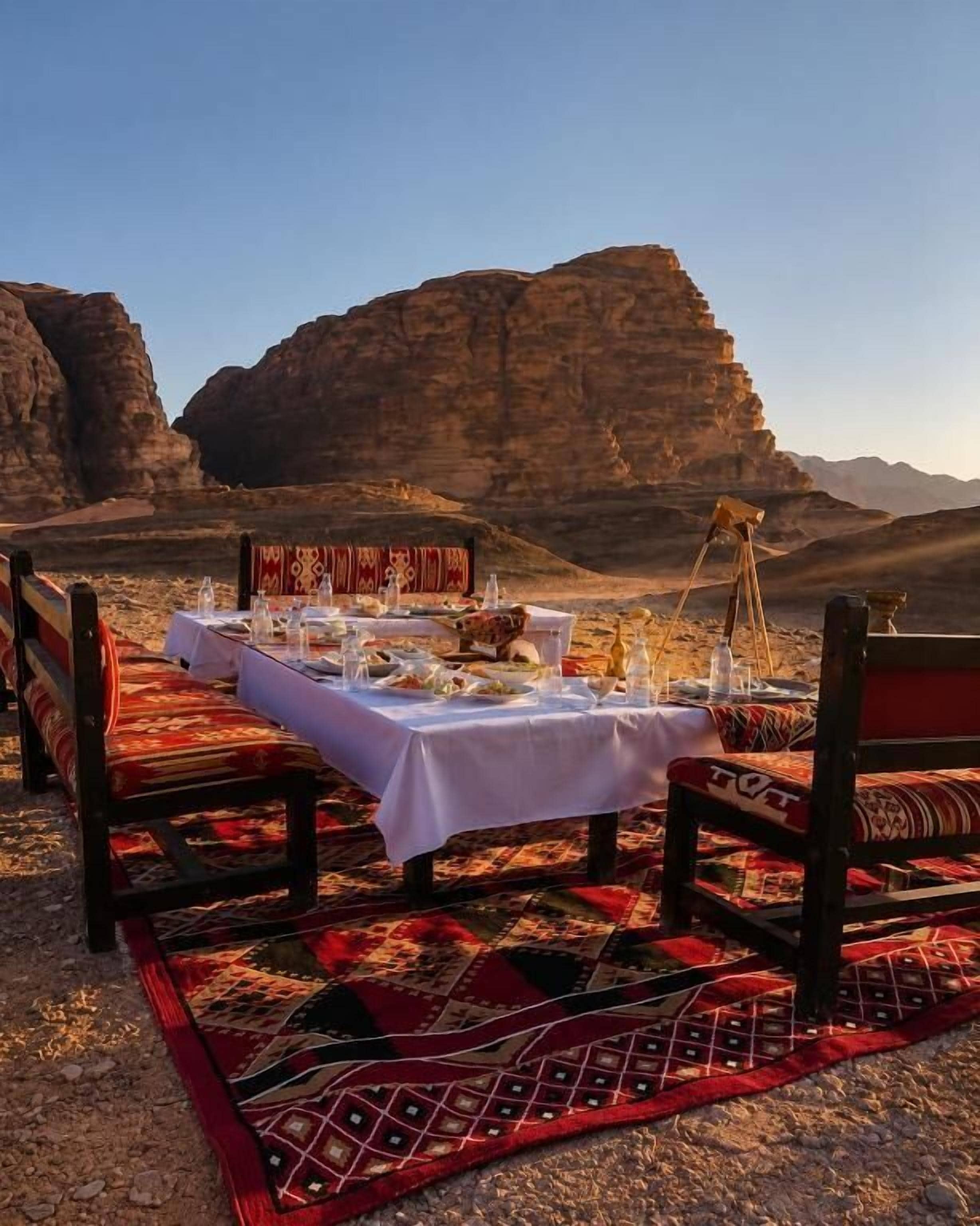 A dining setup with a table and chairs in a desert landscape.