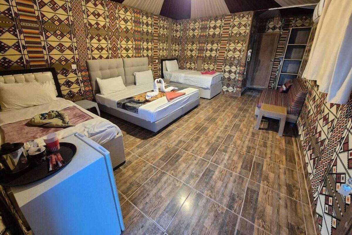 A room with a bed, a sofa, a small table, and a patterned wall.
