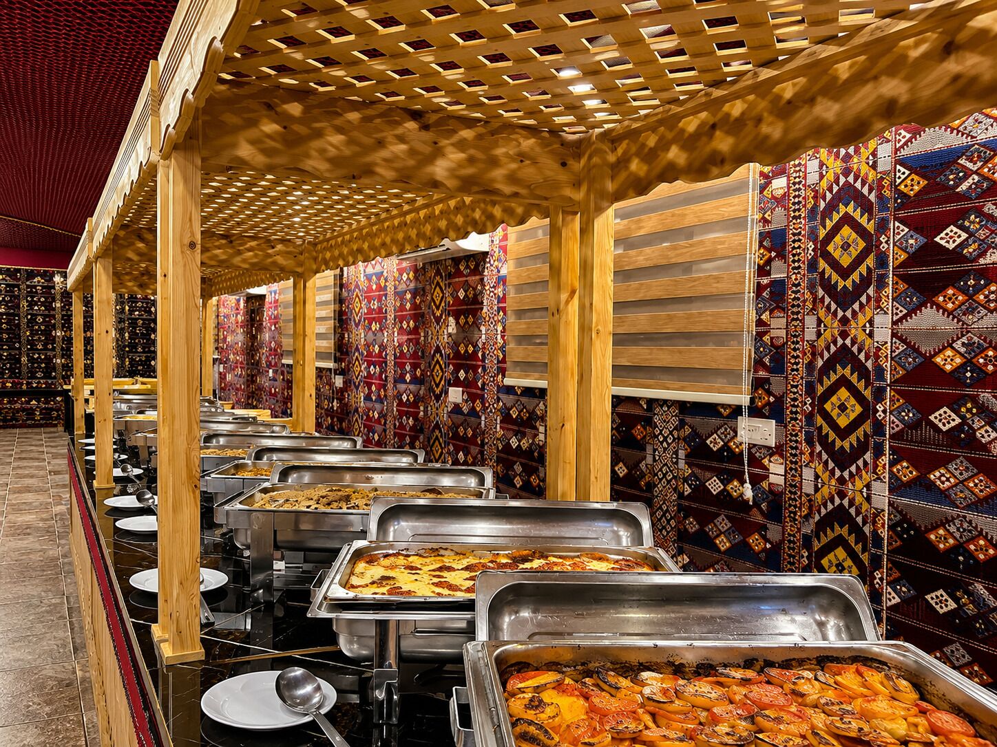 Ein reichhaltiges Buffet mit mehreren Servierstationen und einer Wand mit Muster im Hintergrund.