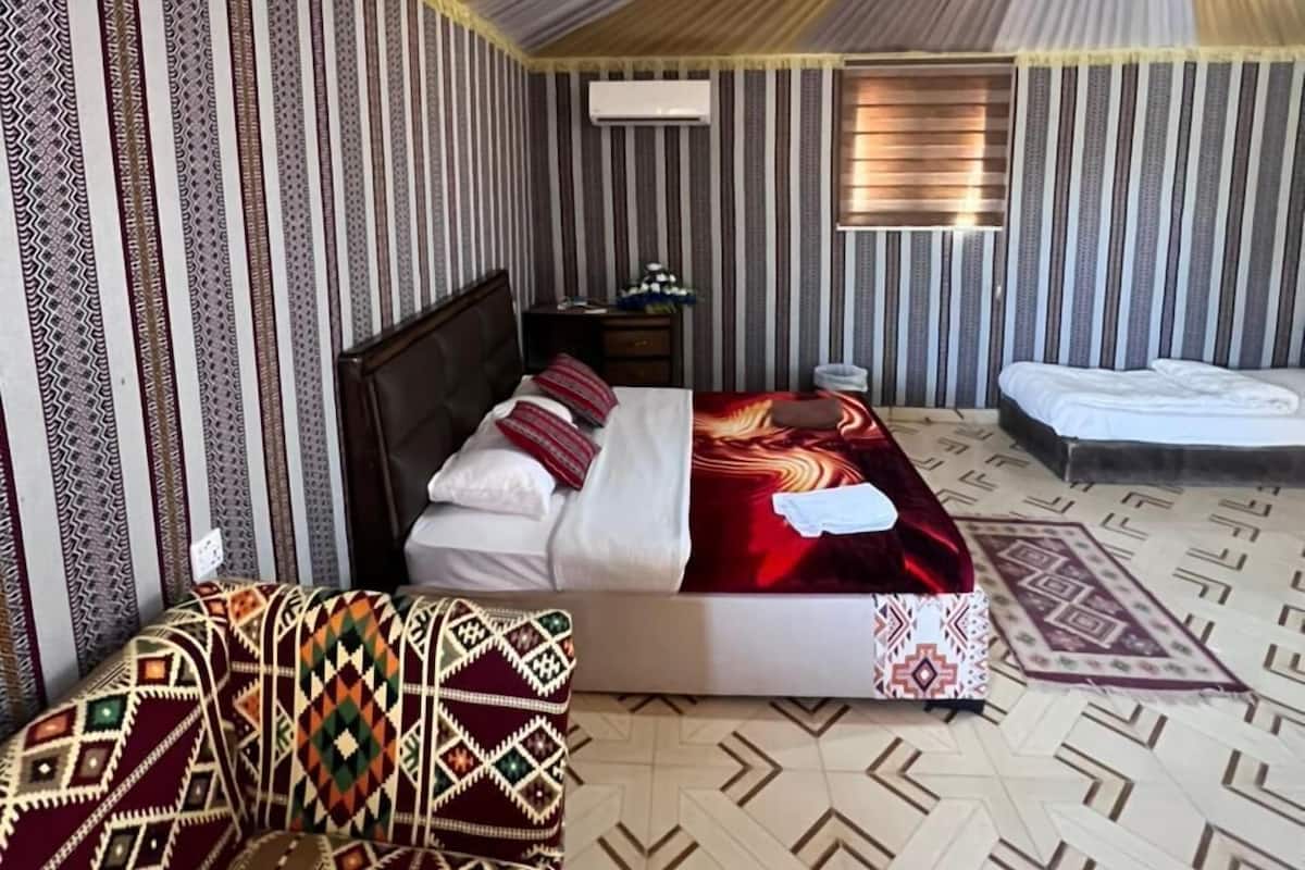 A room with a bed, a sofa, a small table, and a window.