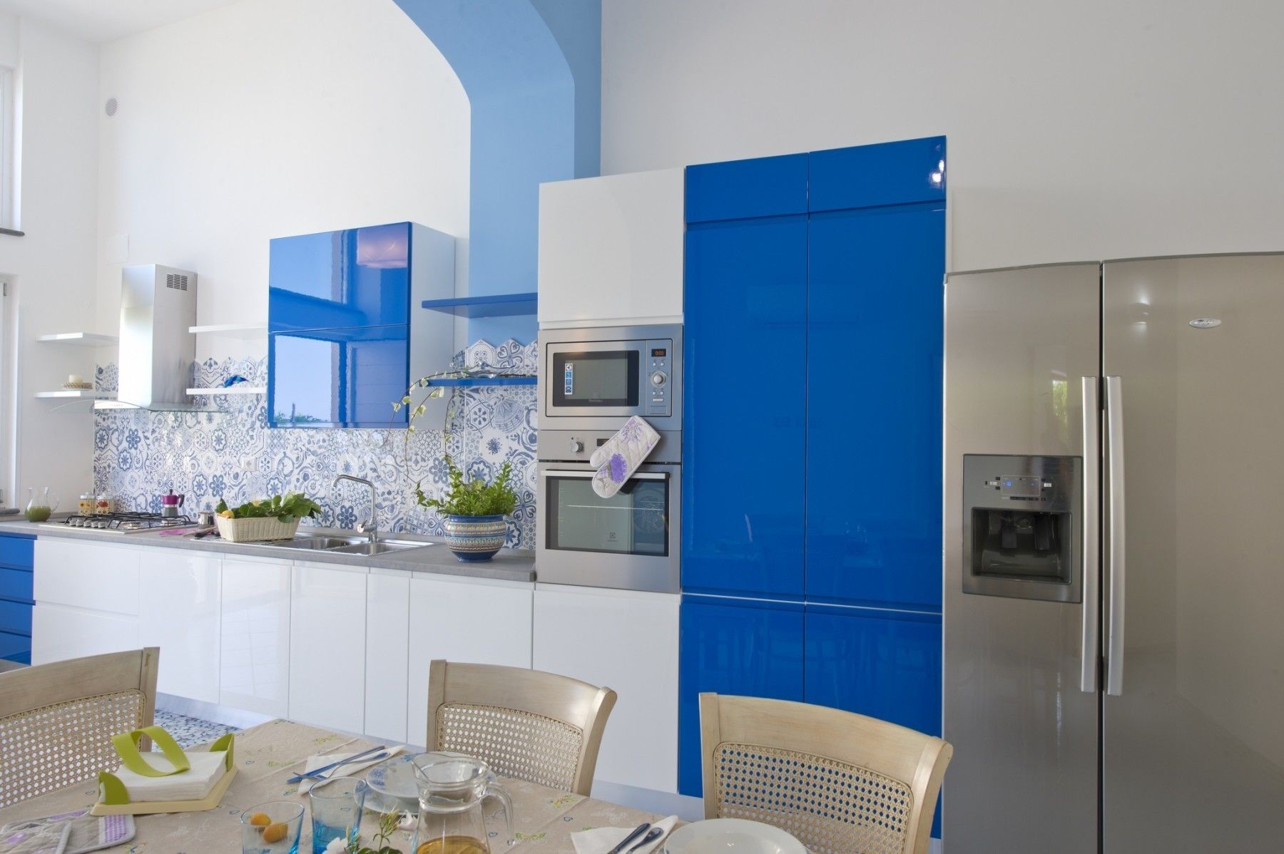 A modern kitchen with blue cabinetry, a stainless steel refrigerator, and a microwave.