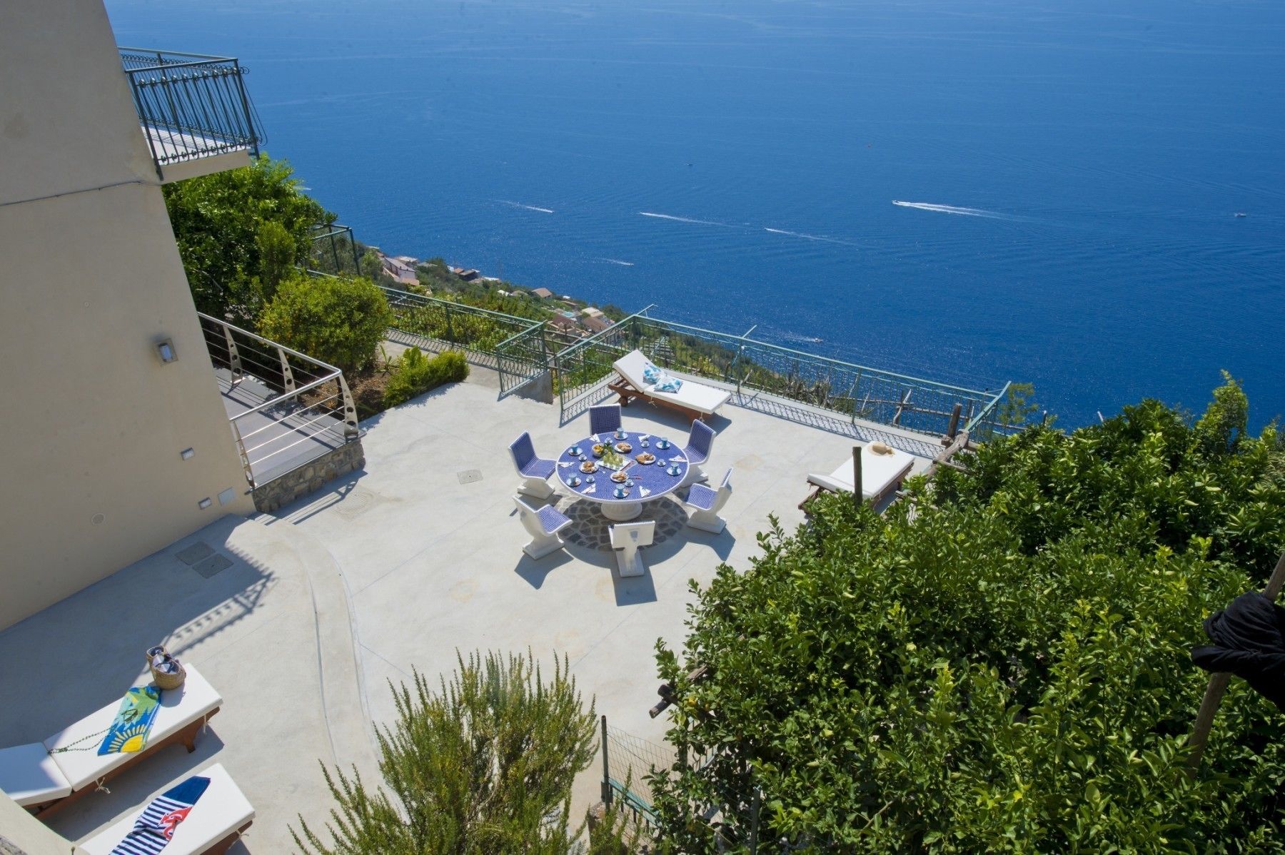 A rooftop terrace with a round table and chairs, overlooking a coastal view.