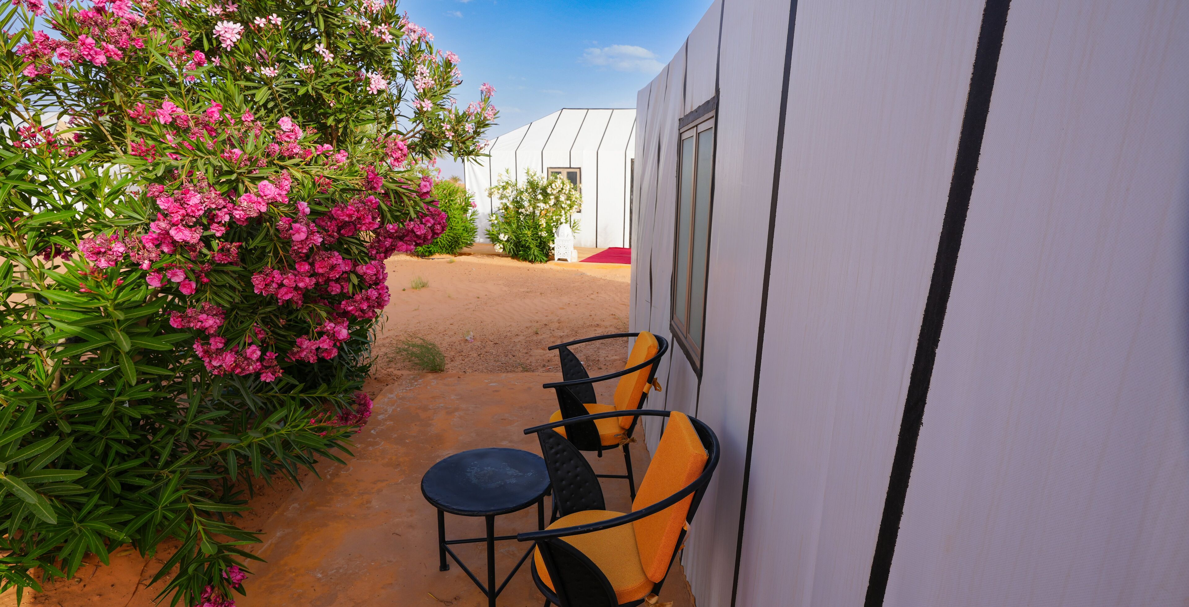 A patio with a white building, a small table, and two chairs.