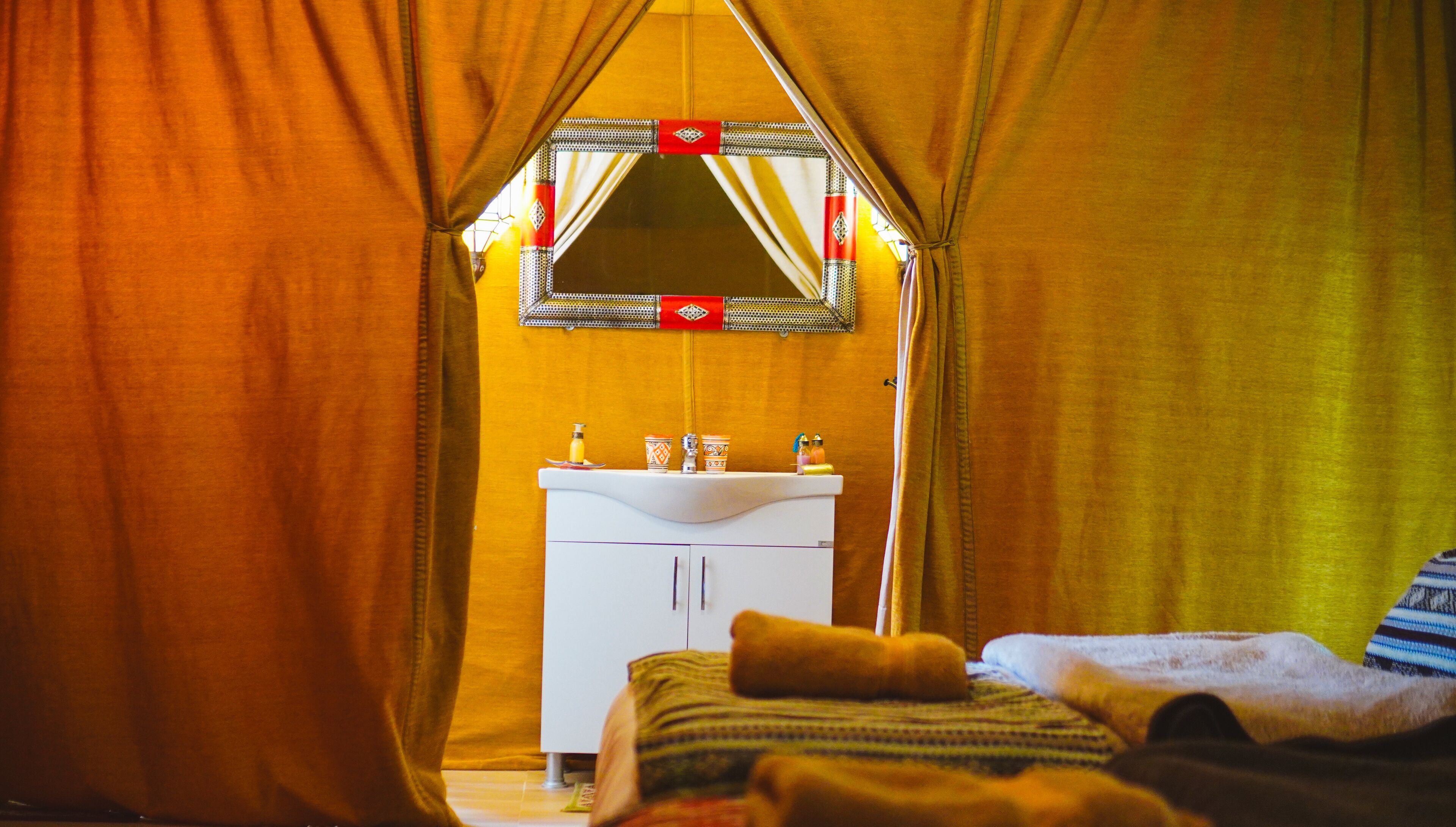 A tent with a white sink and a mirror above it.