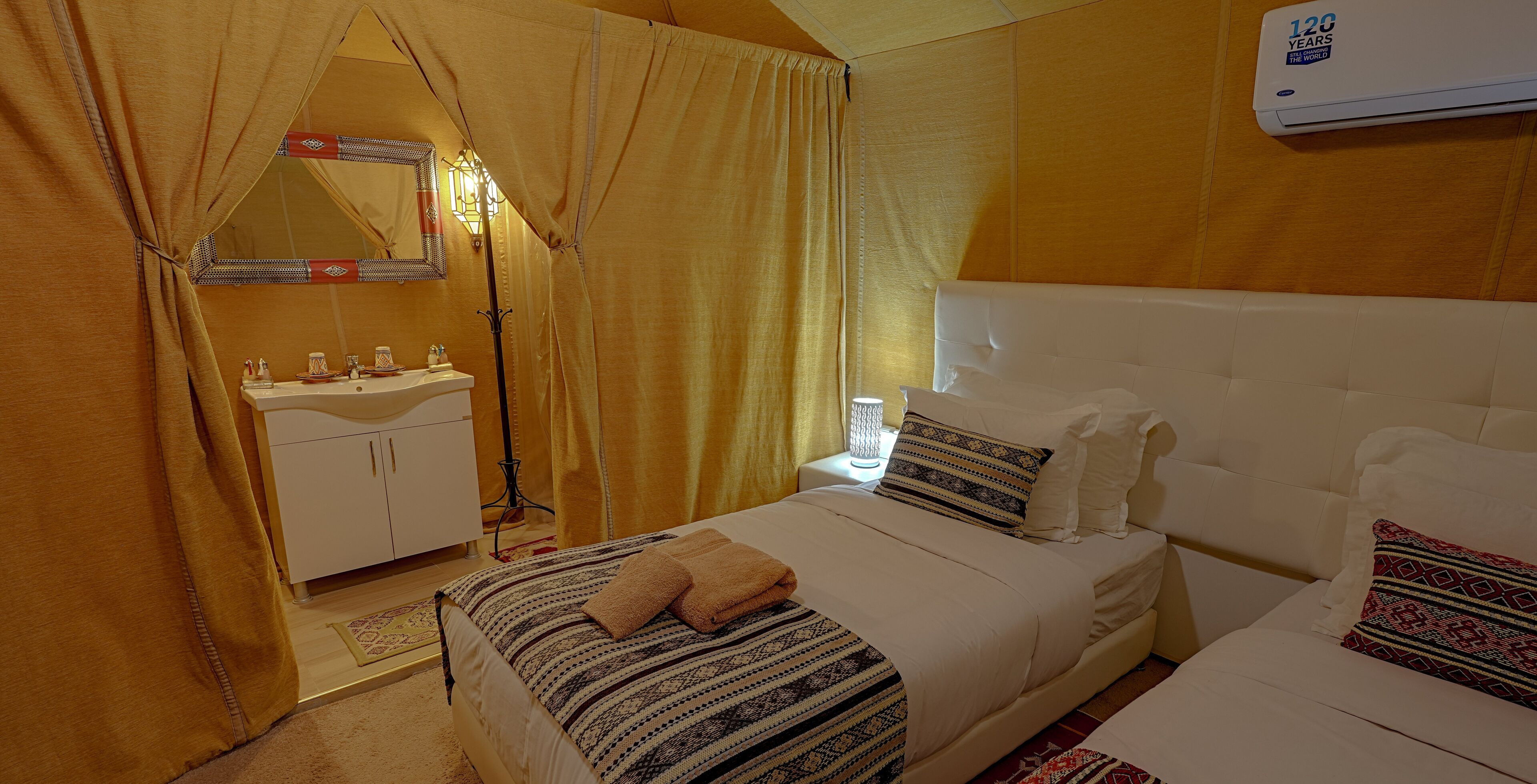 Ein Hotelzimmer mit Bett, Nachttisch, Spiegel, Waschbecken und Fenster.