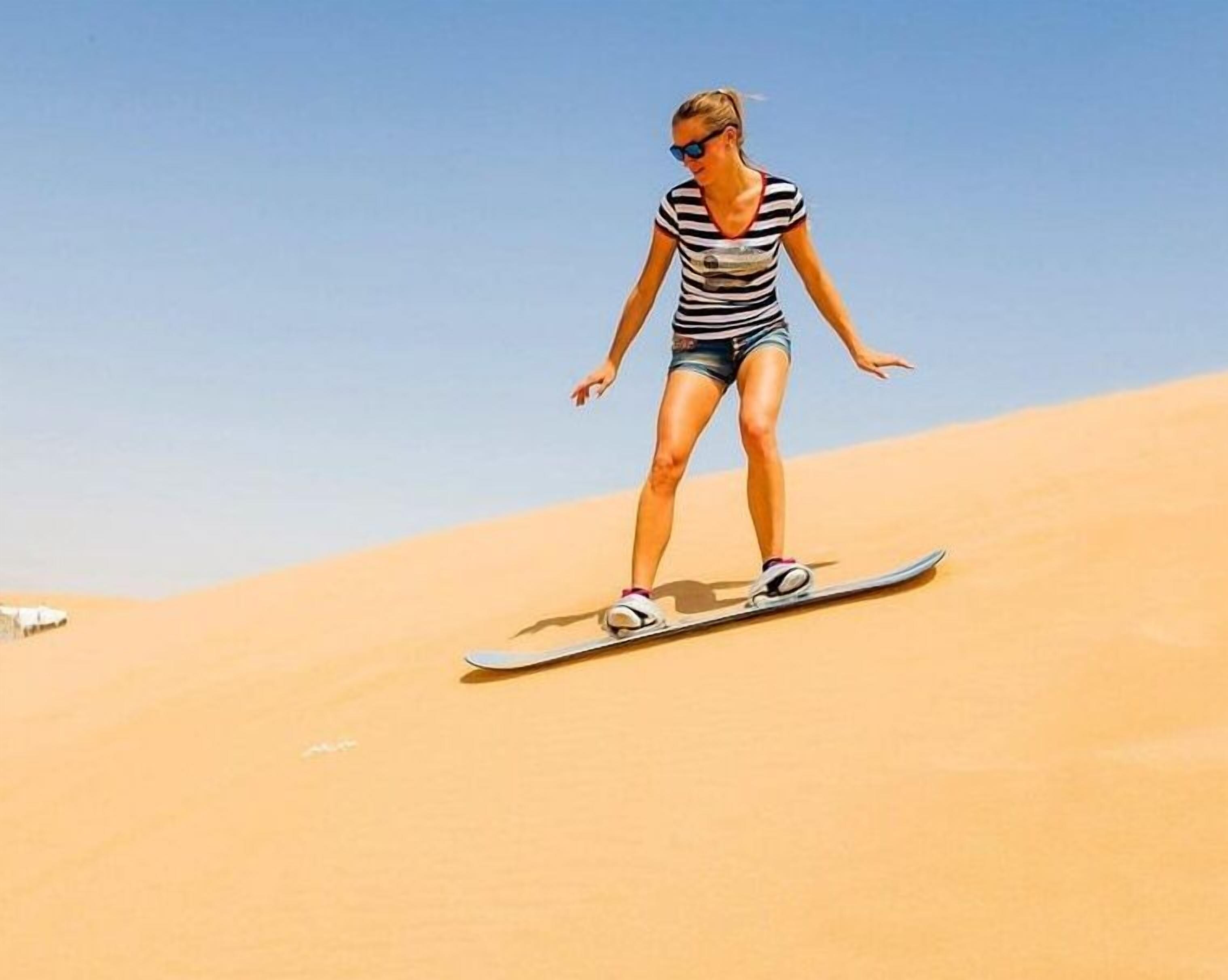 Eine Person snowboardet eine Sanddüne hinunter.