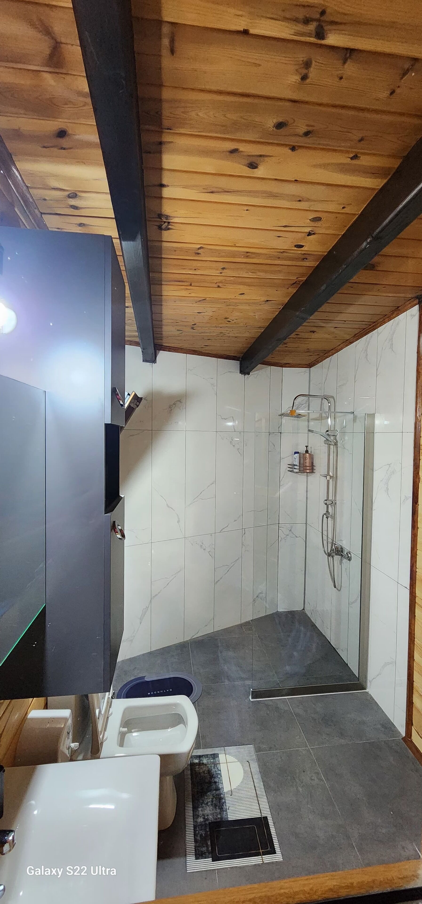 A bathroom with a Galaxy S22 Ultra, a shower, and a toilet.