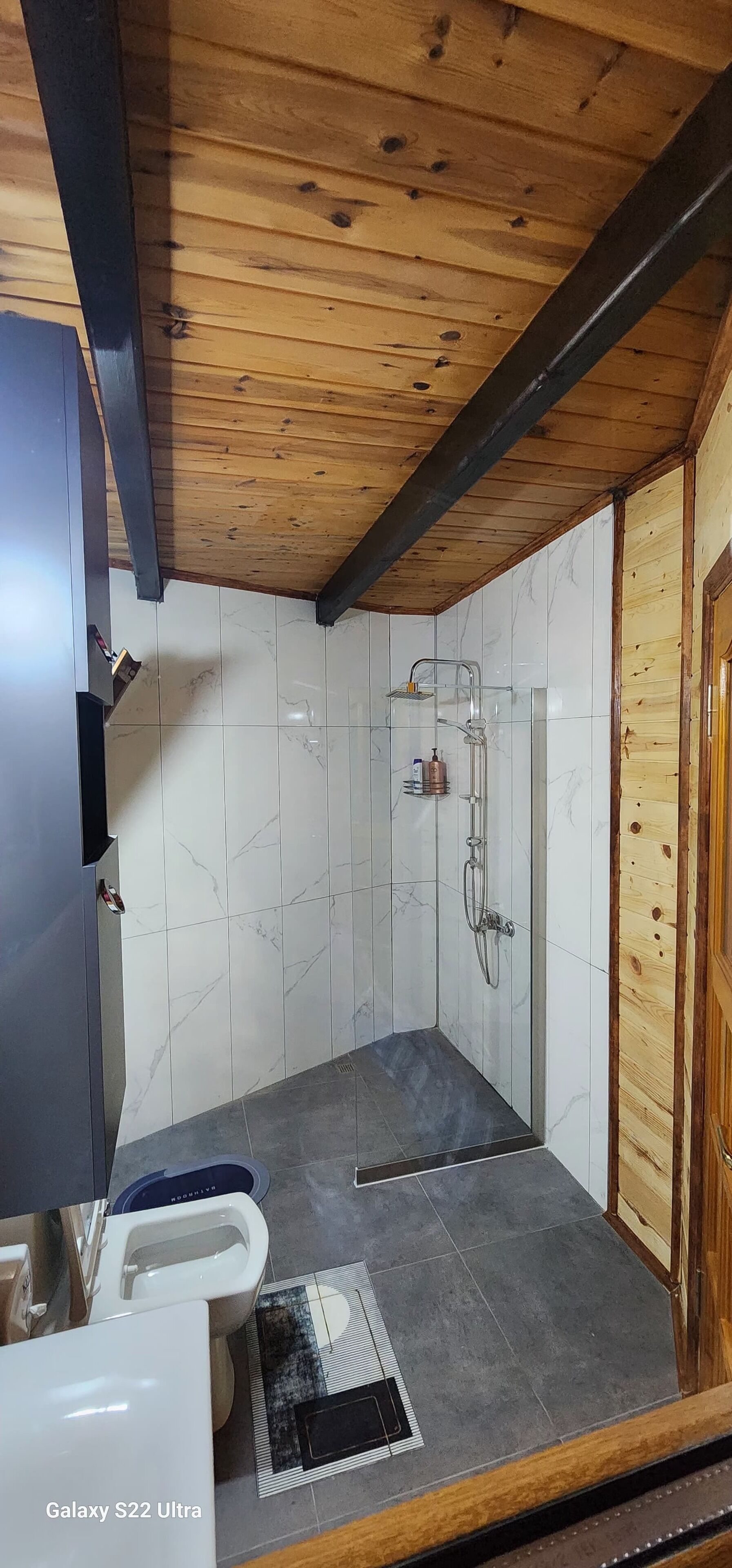 Un baño con un Galaxy S22 Ultra, una ducha y un inodoro.