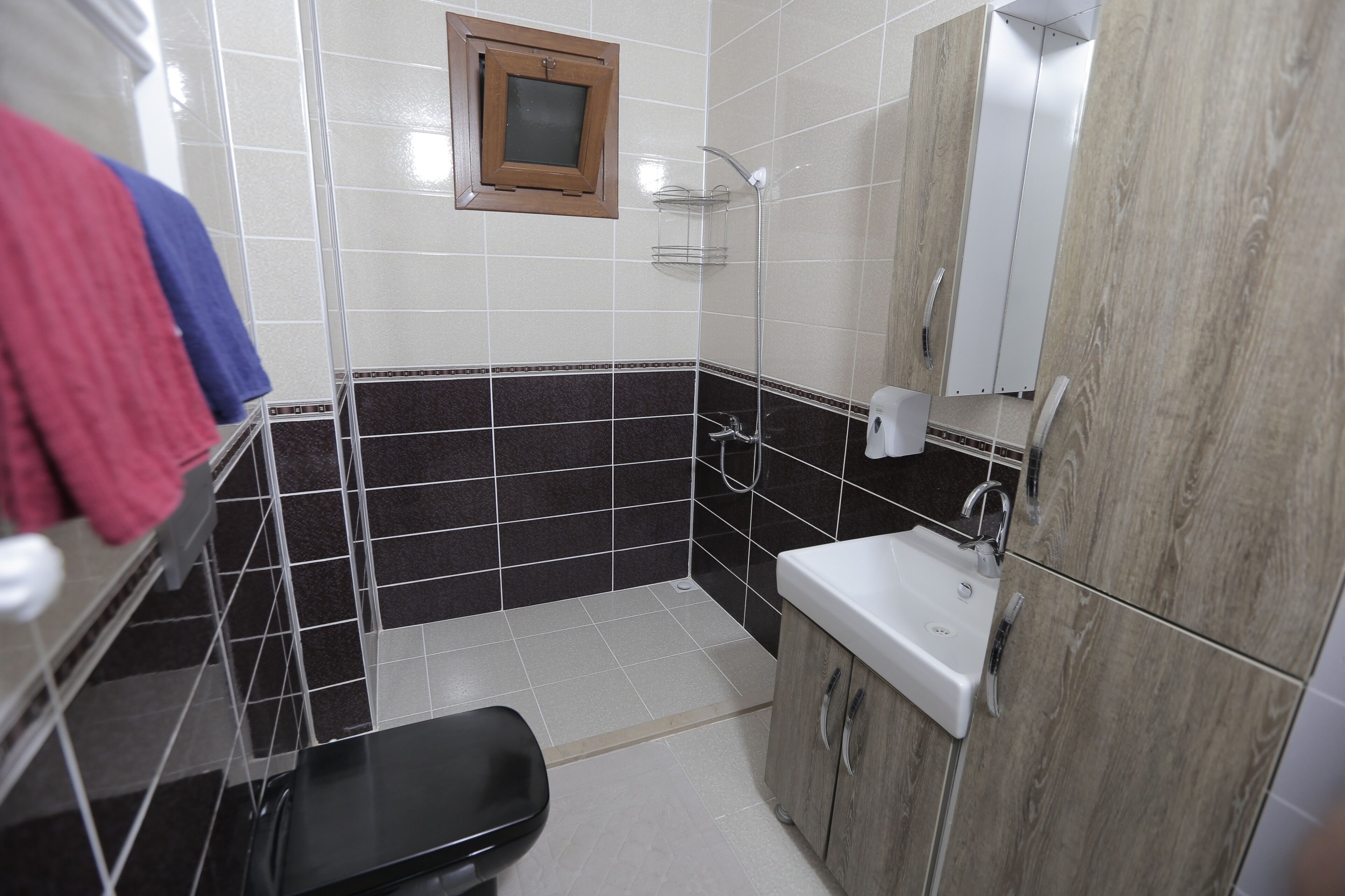 Un baño con suelo de baldosas blanco y negro, un lavamanos blanco, un espejo y una ducha.