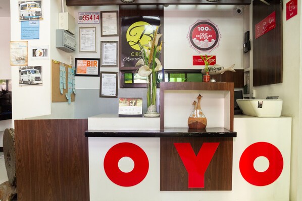 A reception desk with a wooden finish and large red letters spelling "OYO". - Circle-b Apartelle & Suites (Davao)
