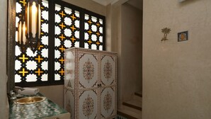 A bathroom with a patterned sink, decorative cabinet, and a window with a geometric design. - Riad Zineb (Marrakech)