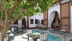 A courtyard with a pool, outdoor seating, and a tree. - Riad Zineb (Marrakech)