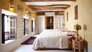 A bedroom with a large bed, wooden beams, a window with curtains, and a small table with a lamp. - Riad Zineb (Marrakech)