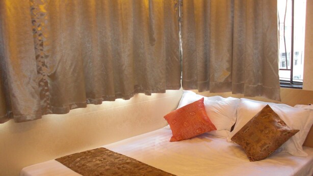 Ein Hotelzimmer mit einem großen Bett, einer gemusterten Tagesdecke und dekorativen Kissen.