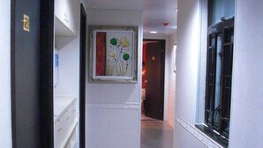 Ein Flur mit einem gerahmten Kunstwerk an der Wand, einer Tür links und einem Fenster rechts.