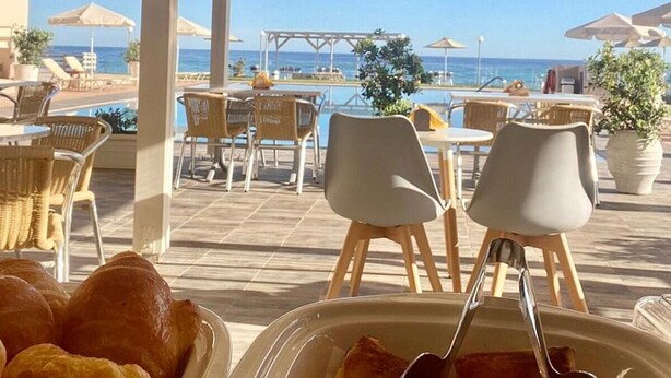 Ett utomhusområde med bord och stolar, med utsikt över en pool och havet.