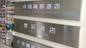 A wall with multiple signs indicating different hotel and apartment names, including "Dynasty Commercial Hotel" and "Empire Commercial Hotel". - Empire Commercial Hotel (Kowloon)
