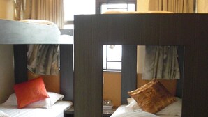 A compact hotel room with bunk beds, a small table, and a window with curtains. - Empire Commercial Hotel (Kowloon)