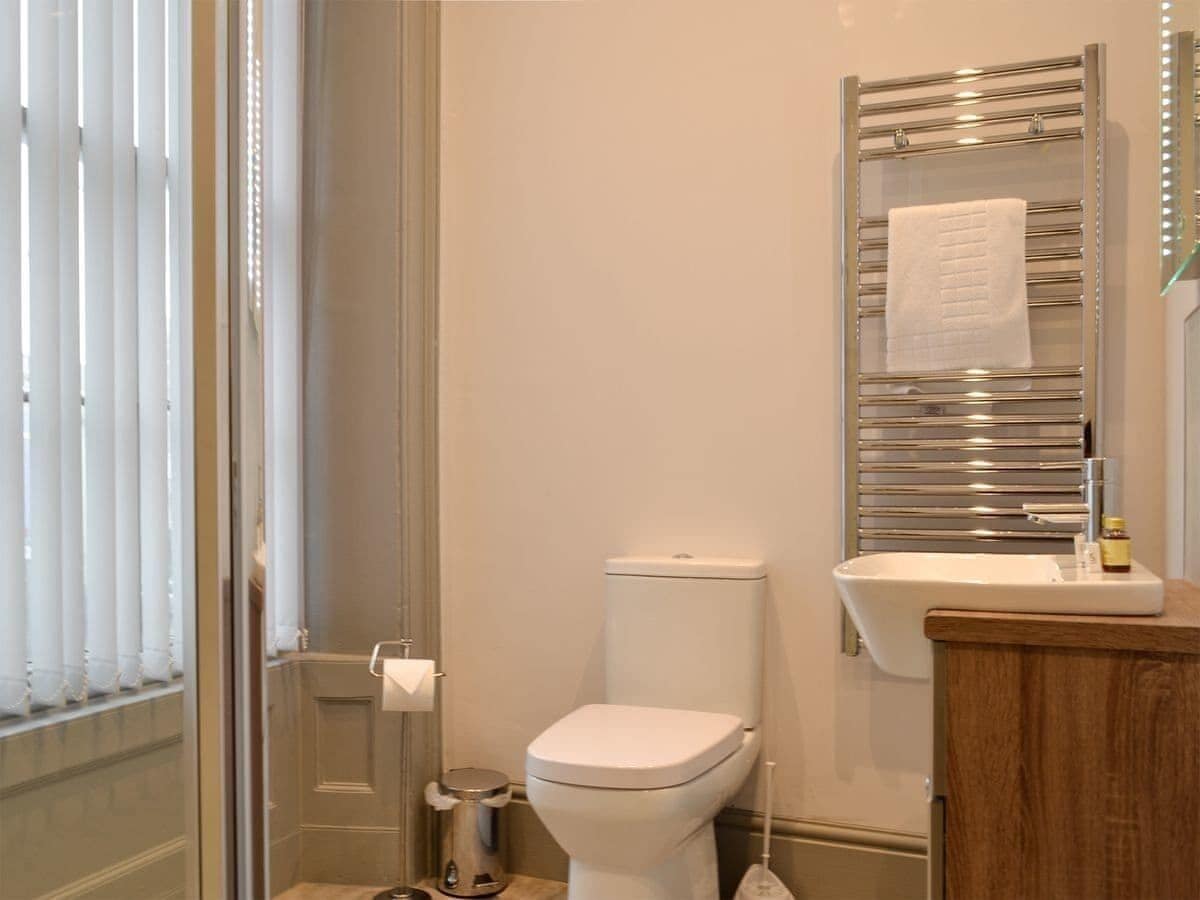 Et badeværelse med toilet, håndvask og håndklædestang.