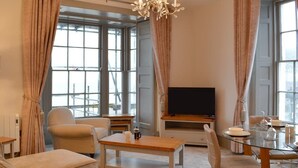 Ein modernes Wohnzimmer mit einer Couch, einem Couchtisch, einem Fernseher und einem Esstisch.
