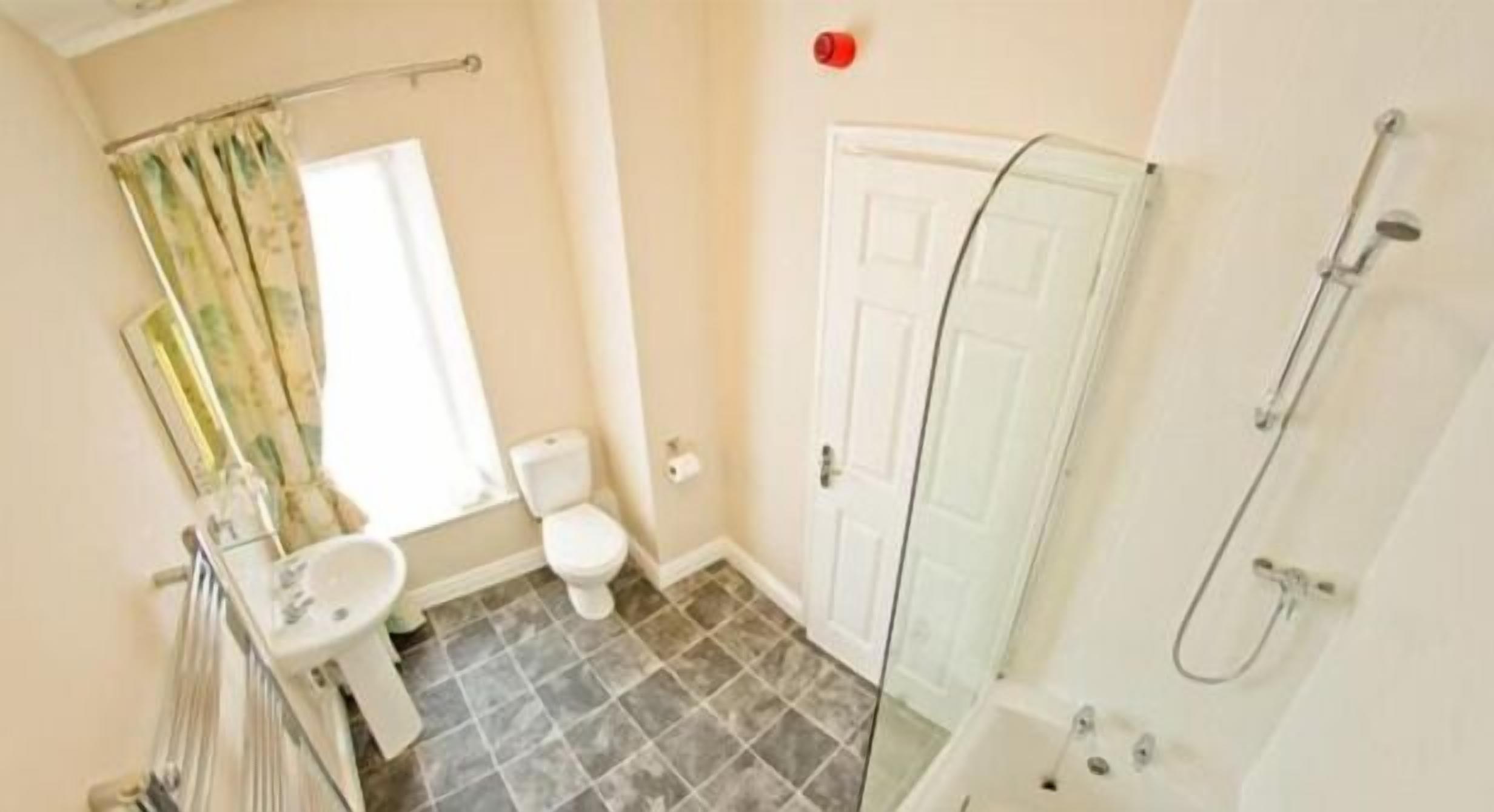Une salle de bain comprenant des toilettes, un lavabo, une douche et une porte.