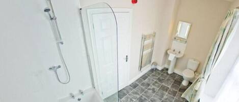 Une salle de bain avec douche, toilettes et lavabo.
