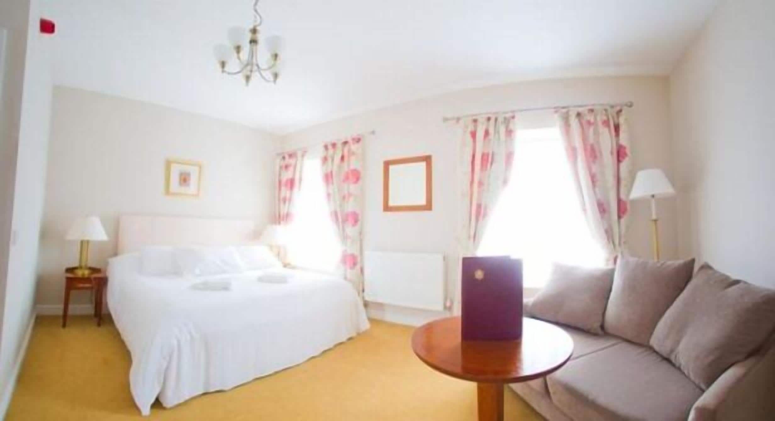 Una habitación de hotel con cama, sofá, una mesa redonda y cortinas.