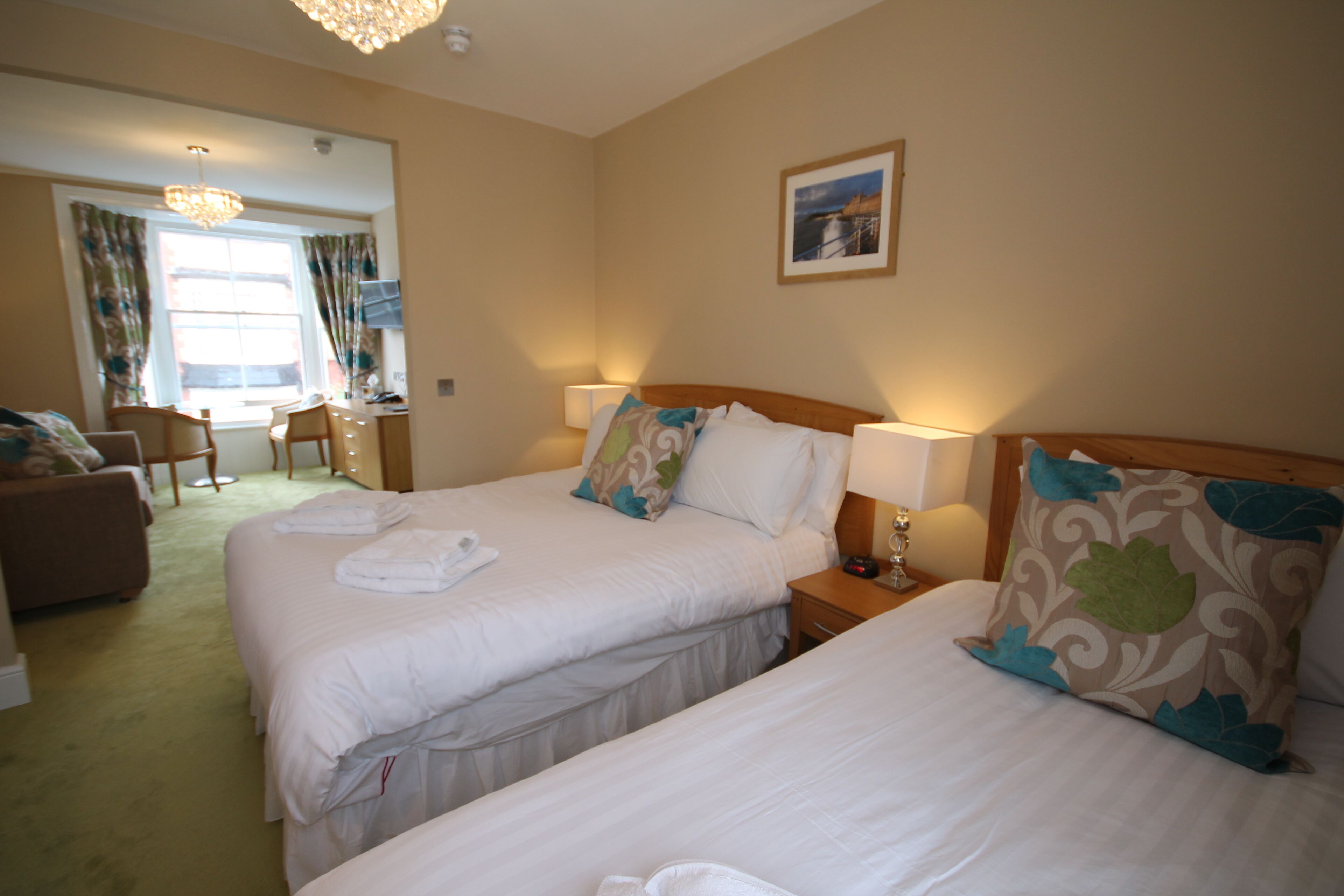 A hotel room with two beds, a desk, and a chair.