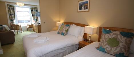 A hotel room with two beds, a desk, and a chair.