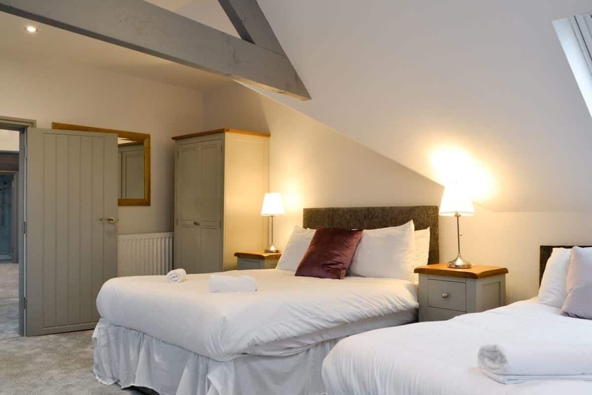 Una habitación de hotel con dos camas, un armario y un espejo.