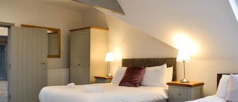 Una habitación de hotel con dos camas, un armario y un espejo.