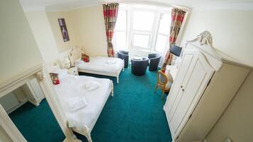 A hotel room with two beds, a desk, a chair, and a wardrobe.