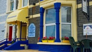 Un edificio con toldo amarillo, escalera azul y un cartel que indica un hotel.