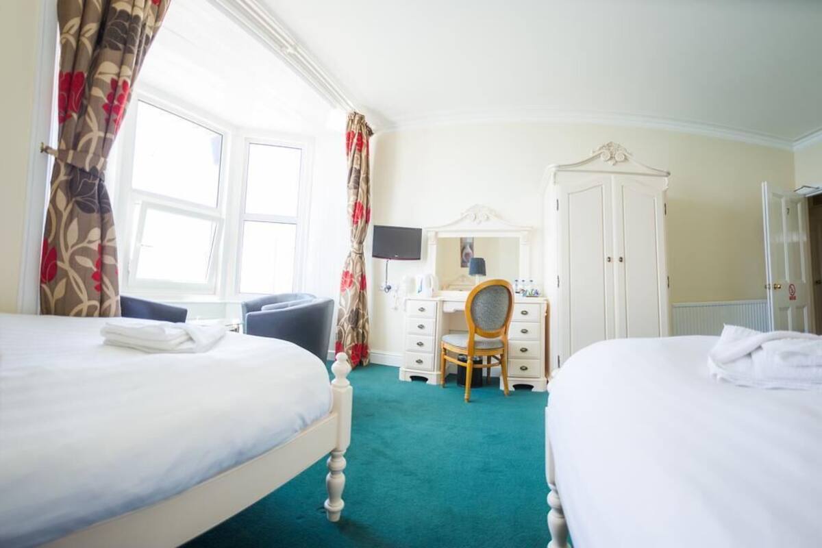 A hotel room with two beds, a desk with a chair, a television, and a wardrobe.