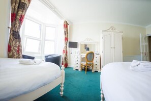 A hotel room with two beds, a desk with a chair, a television, and a wardrobe. - Queensbridge Hotel (Aberystwyth)