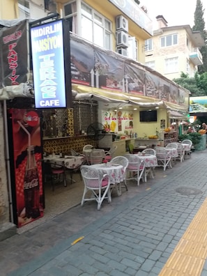 A cafe with outdoor seating, a Coca-Cola advertisement, and a sign for 'Midirlk Mansiyon Cafe'. - Hidirlik Pansiyon (Antalya)