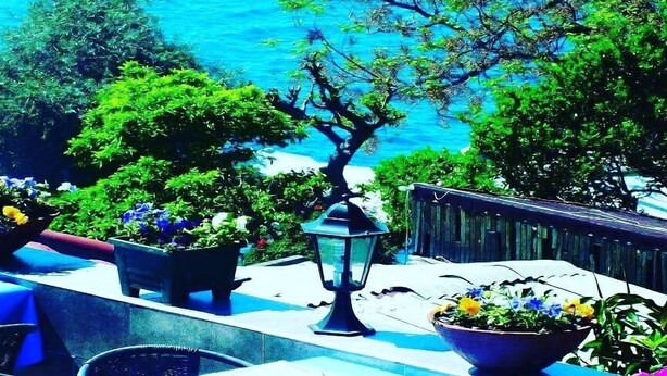 A terrace restaurant with outdoor seating, potted plants, and a view of the sea. - Hidirlik Pansiyon (Antalya)