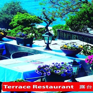 A terrace restaurant with outdoor seating, potted plants, and a view of the sea. - Hidirlik Pansiyon (Antalya)
