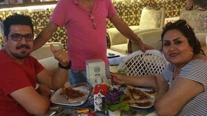A dining area with wicker chairs, a table with plates of food, and a decorative wall with patterned curtains. - Hidirlik Pansiyon (Antalya)