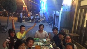 A group of people dining outdoors at night with a table full of food and drinks. - Weihai Hiking International Youth Hostel (Weihai)