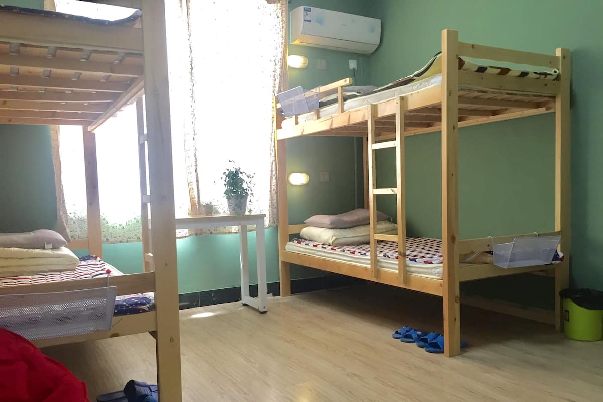 Un dormitorio con literas, una mesita pequeña y una ventana con cortinas.