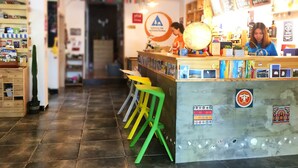 A hostel interior with a reception desk, colorful stools, and various travel-related items displayed. - Weihai Hiking International Youth Hostel (Weihai)