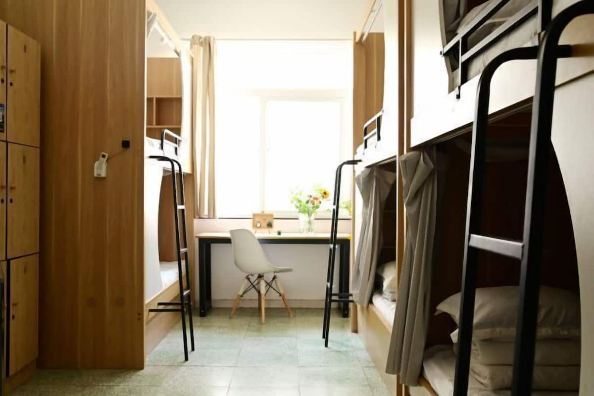 Un dormitorio con literas, un escritorio, una silla y una ventana con cortinas.