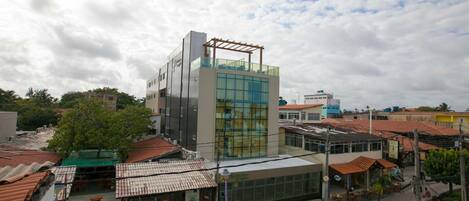 A modern building with a glass facade and a wooden pergola on the rooftop.