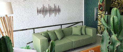 A modern living room with a green striped sofa, a white armchair, a wooden coffee table, and a cactus plant.